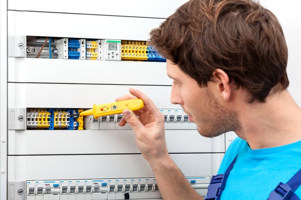 Repairman checking a voltage and fixing a switchboard