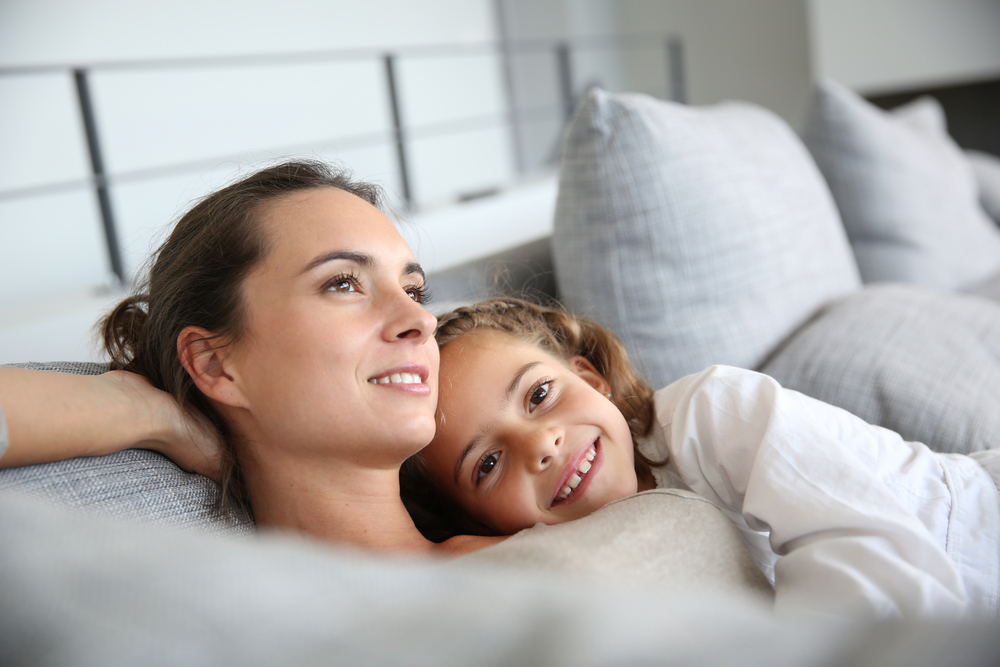 Mom and little girl relaxing in sofa